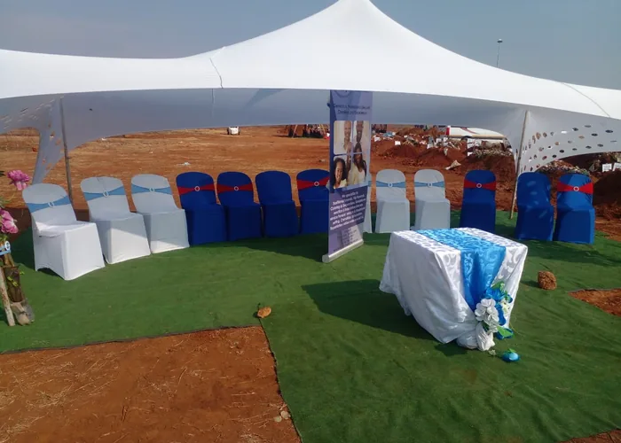 A white stretch tent and seating prepared at a graveside