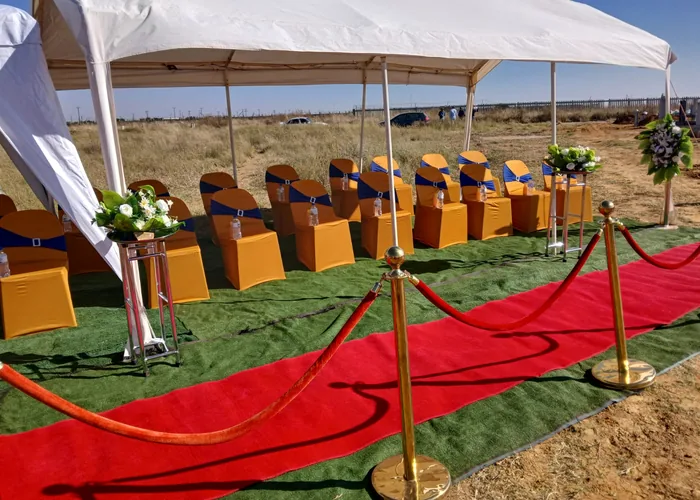 Red carpet, gold stanchions and seating prepared under a tent