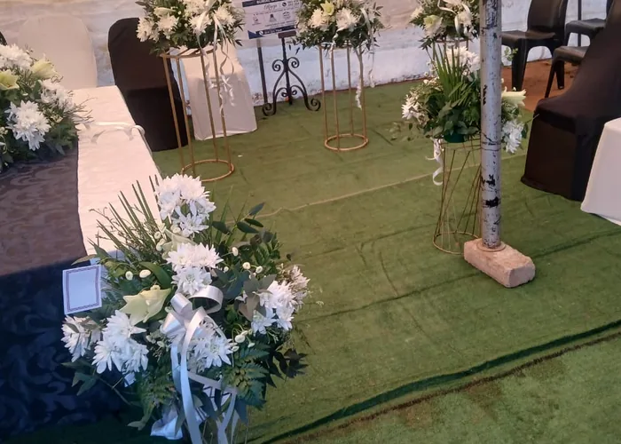 White floral arrangements on stands inside a service tent