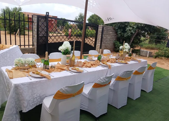 An outdoor table laid with white and gold settings