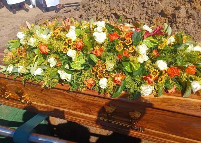 A floral spray arranged on a coffin at the graveside