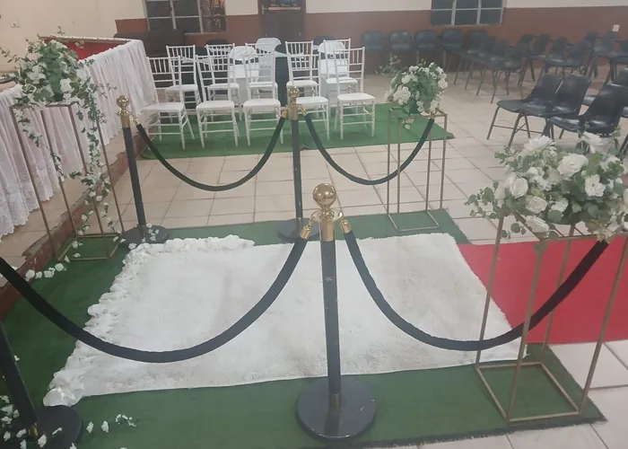 A venue prepared with carpet, stanchions and floral arrangements