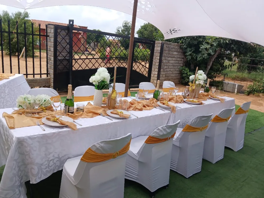 A table laid with white and gold settings at a Bambanani service